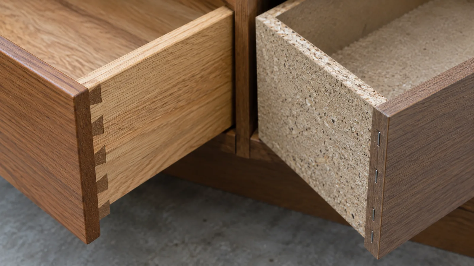 Two open drawers side by side: one with interlocking dovetail joints at the corner and one with a stapled butt joint in particleboard